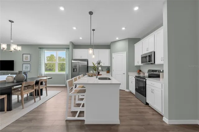 a large kitchen with kitchen island a large island a stove a dining table and chairs