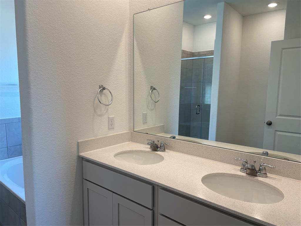 129 Starflower Cove Georgetown, TX 78628 - Photo 14 of 31 Full bath featuring a textured wall, double vanity, a shower stall, and a garden tub