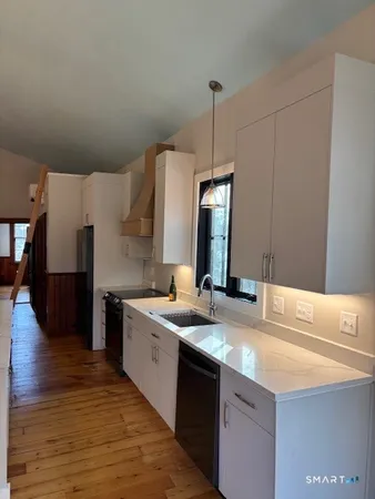 a kitchen with stainless steel appliances granite countertop a sink a stove and a wooden floors