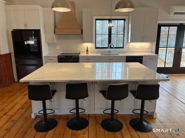 a kitchen with granite countertop a counter space chairs cabinets and stainless steel appliances