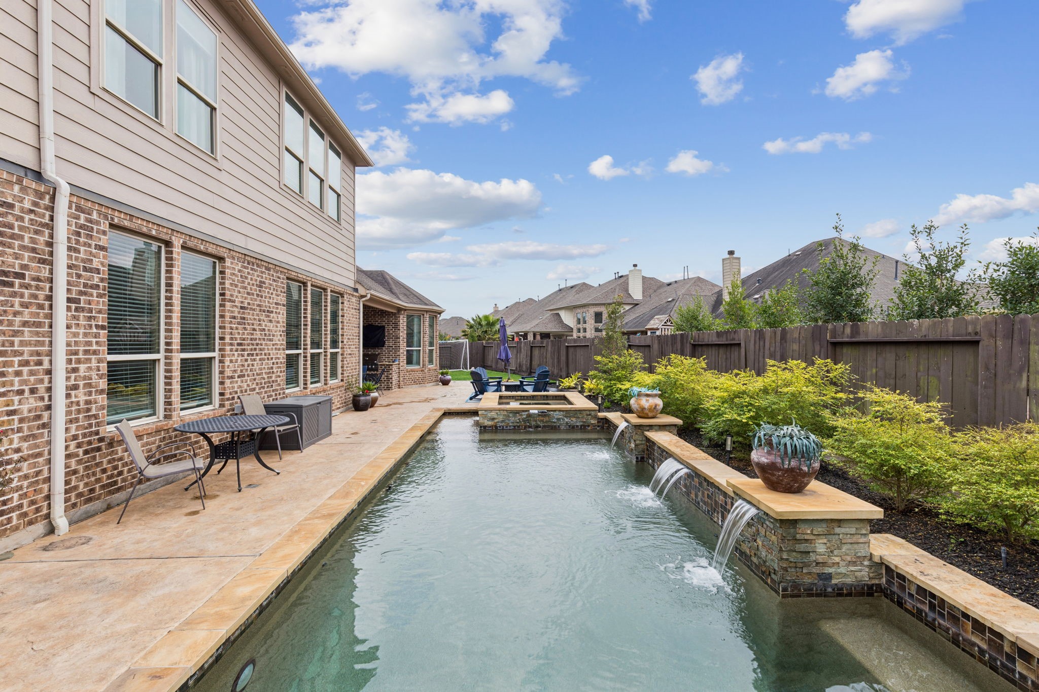 1118 Fragile Sail Court Katy, TX 77494 - Photo 25 of 36 Resort-style backyard retreat featuring a sleek lap pool with cascading water features, raised spa, and elegant stone accents. The expansive patio and manicured landscaping create a private outdoor oasis perfect for relaxing or entertaining.