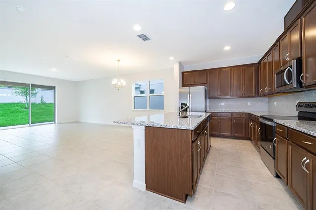 a kitchen with stainless steel appliances granite countertop a stove top oven a sink dishwasher and a microwave oven with large wooden cabinets