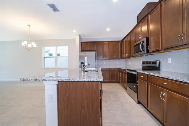 a kitchen with stainless steel appliances granite countertop a sink a stove and cabinets