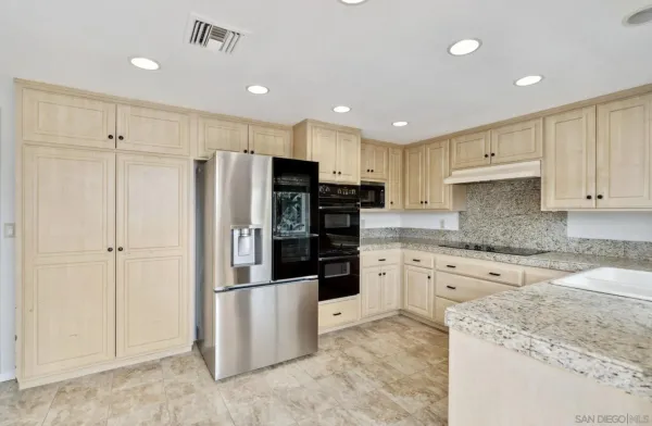 a kitchen with granite countertop a refrigerator and cabinets