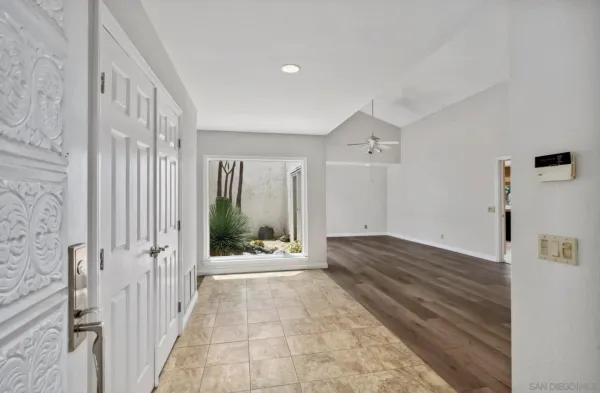 a view of a hallway to a livingroom with wooden floor and white doors