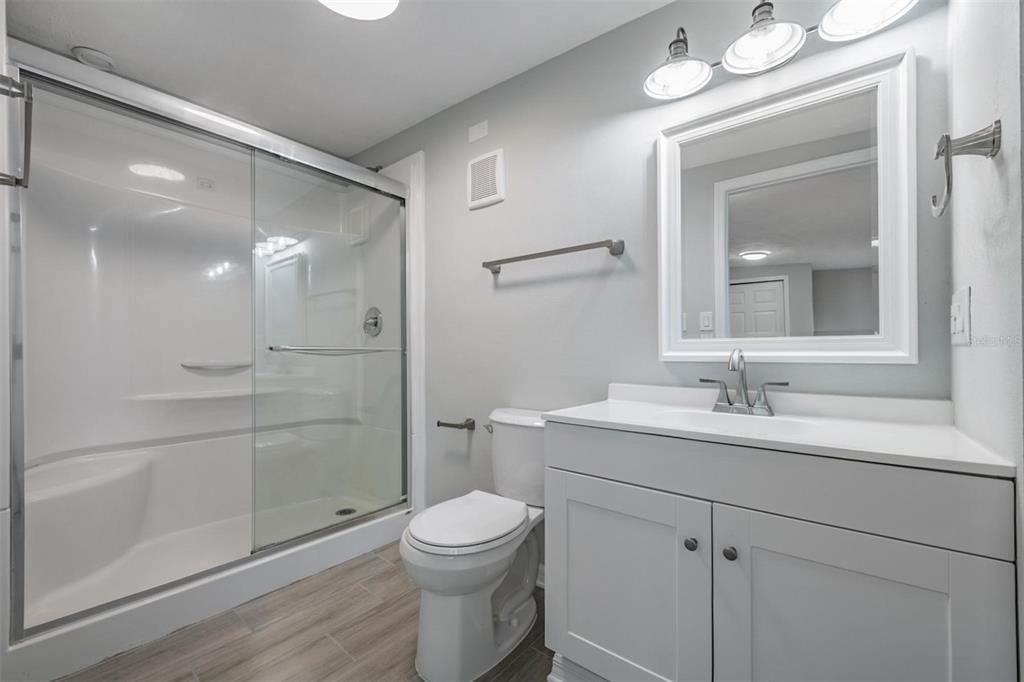7806 Butler Avenue Hudson, FL 34667 - Photo 17 of 31 a bathroom with a toilet a sink a glass door a shower and vanity