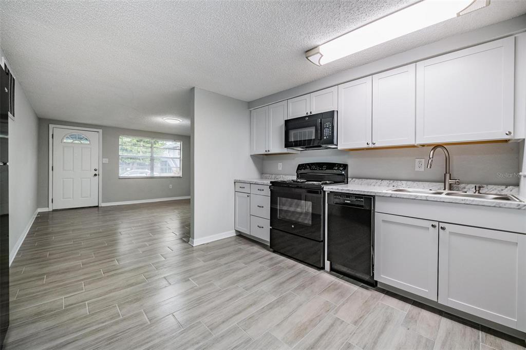 7806 Butler Avenue Hudson, FL 34667 - Photo 6 of 31 a kitchen with granite countertop a stove top oven a sink dishwasher and a microwave oven on the wooden floor