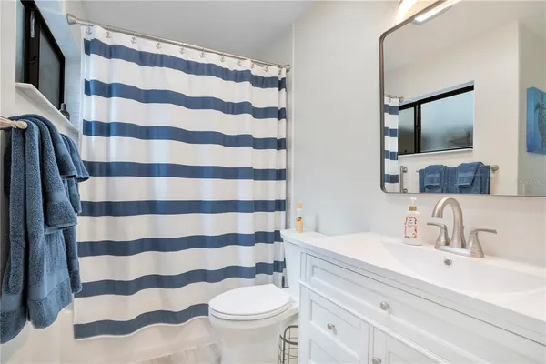 a bathroom with a sink a toilet a mirror and shower curtain