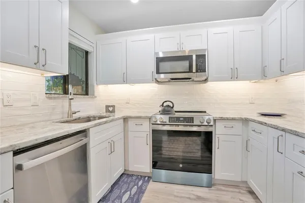 a kitchen with granite countertop white cabinets stainless steel appliances and a sink