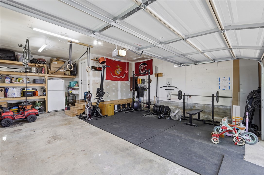 515 Crescent Drive Bryan, TX 77801 - Photo 32 of 43 Spacious two-car garage featuring a concrete floor, built-in shelving, overhead fluorescent lighting, a service door, and steps leading into the interior