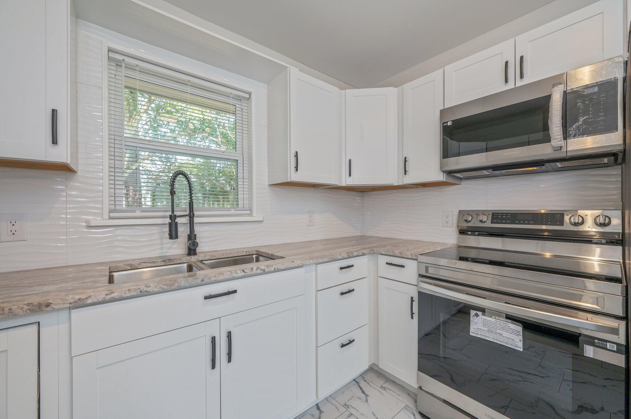 22543 Highway 331 Laurel Hill, FL 32567 - Photo 8 of 36 a kitchen with granite countertop white cabinets stainless steel appliances and a sink