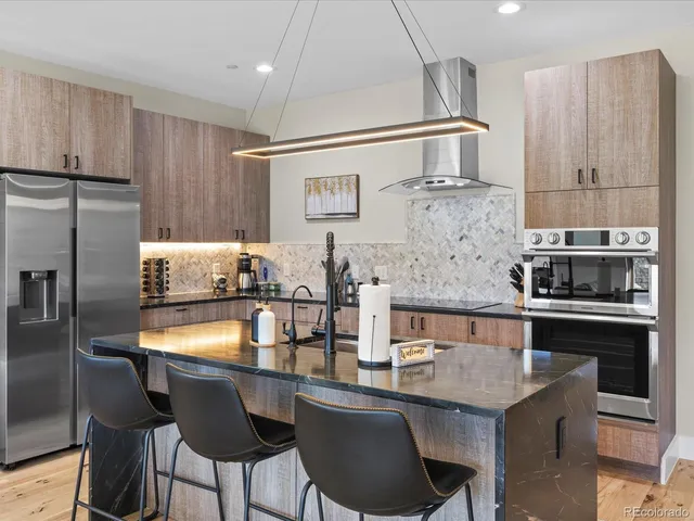 a kitchen with granite countertop a table chairs stove and refrigerator
