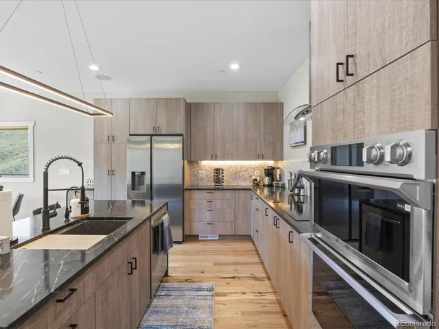 a kitchen with stainless steel appliances granite countertop a sink a stove and refrigerator