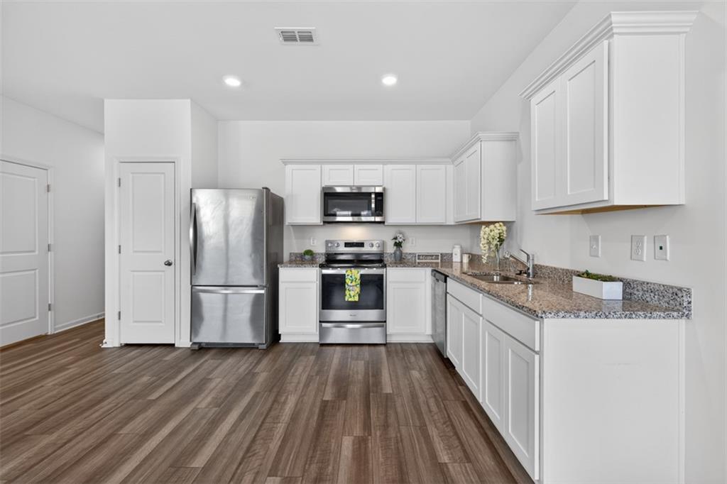 64 Thetford Way Winder, GA 30680 - Photo 11 of 41 a kitchen with granite countertop a refrigerator oven a sink dishwasher and a stove with wooden floor