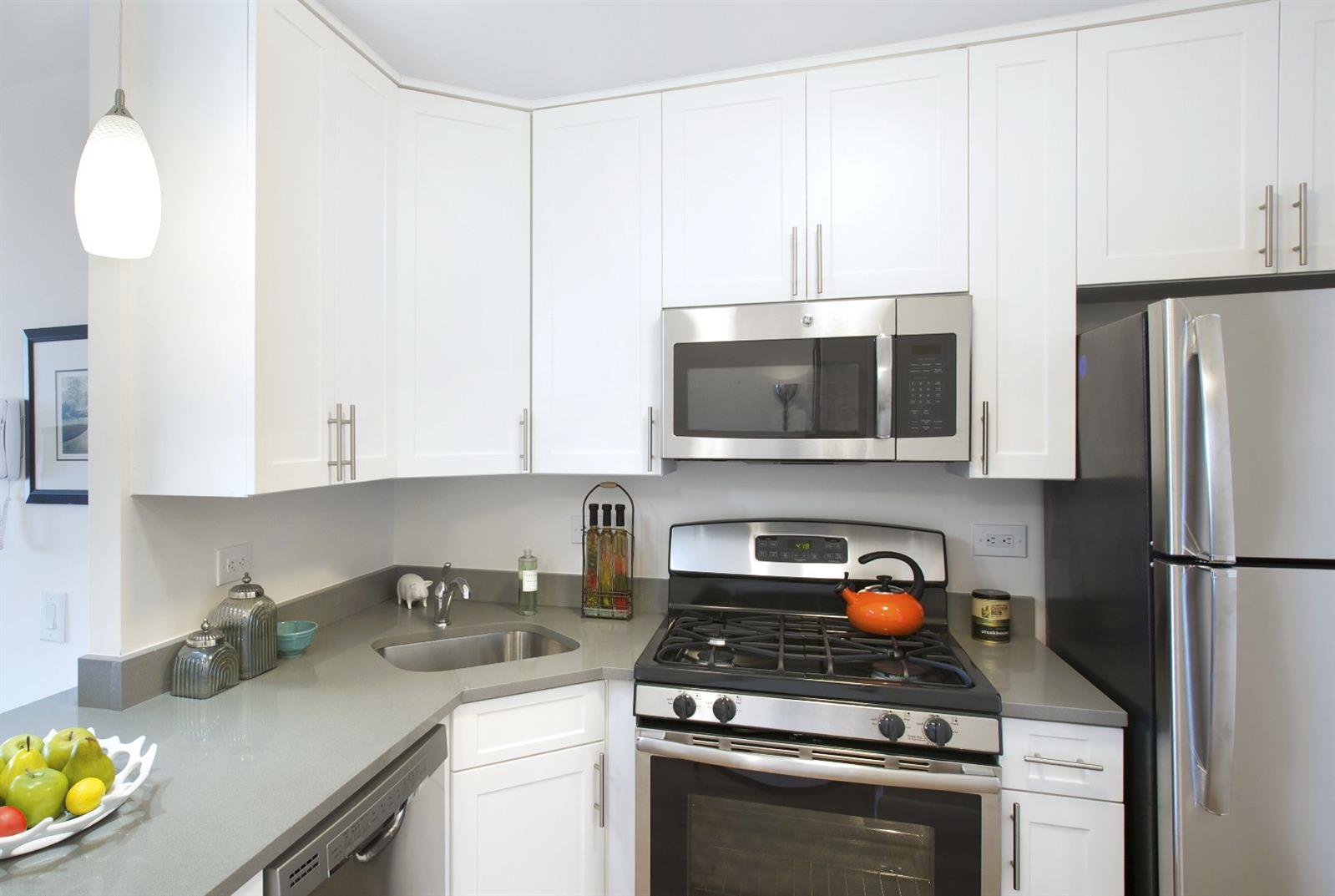 a kitchen with stainless steel appliances granite countertop a stove a refrigerator and a white cabinets