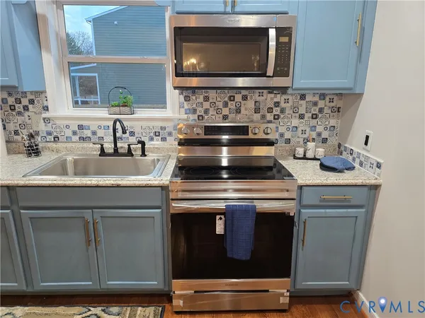 a kitchen with granite countertop a sink and a stove top oven