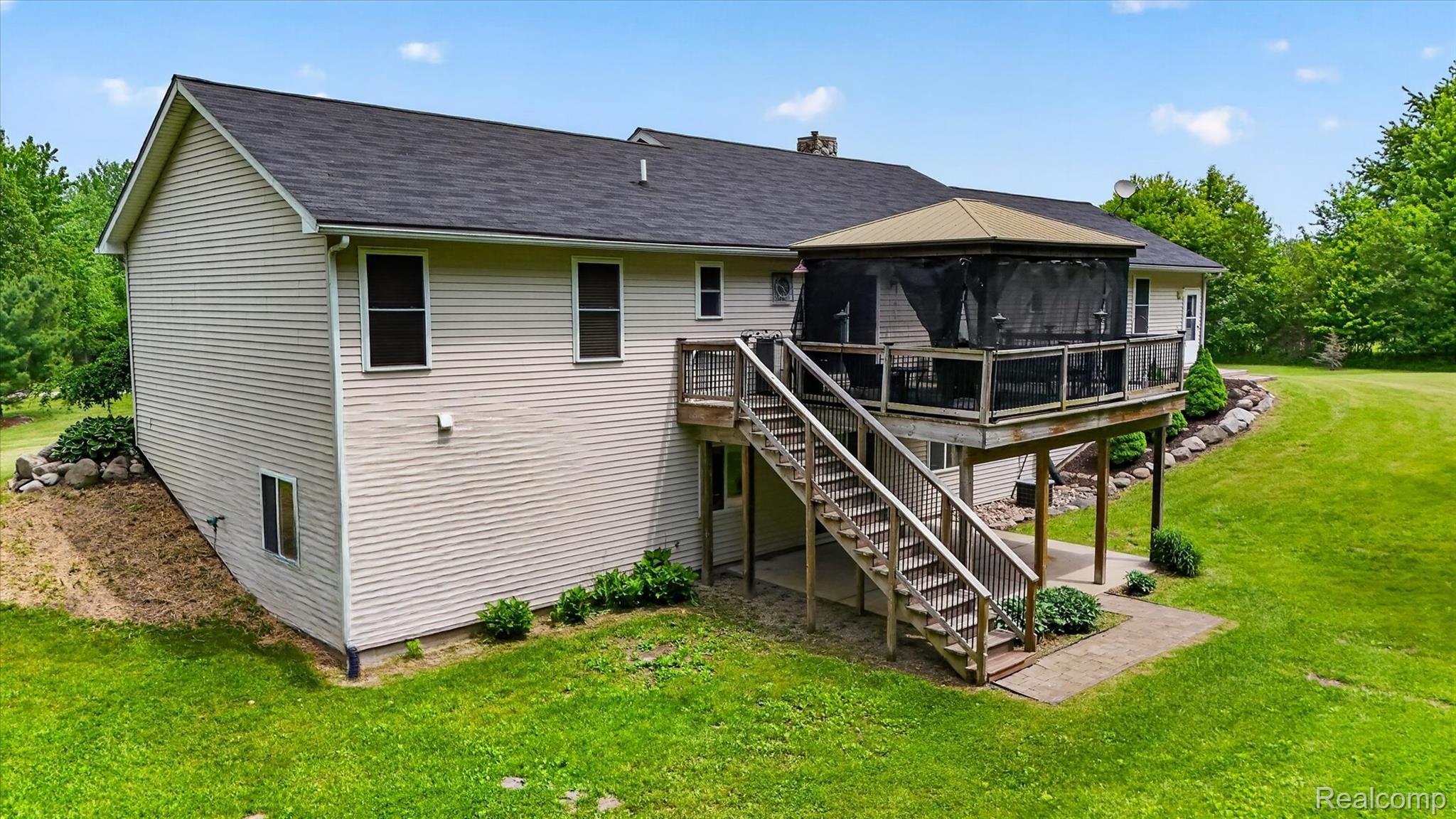 9565 Crofoot Road Fowlerville, MI 48836 - Photo 51 of 63 Rear exterior featuring a spacious elevated deck with a screened gazebo, leading to a ground-level concrete patio