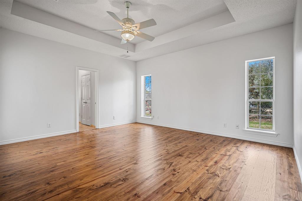 5327 Dusty Road Athens, TX 75752 - Photo 18 of 35 an empty room with wooden floor chandelier fan and windows