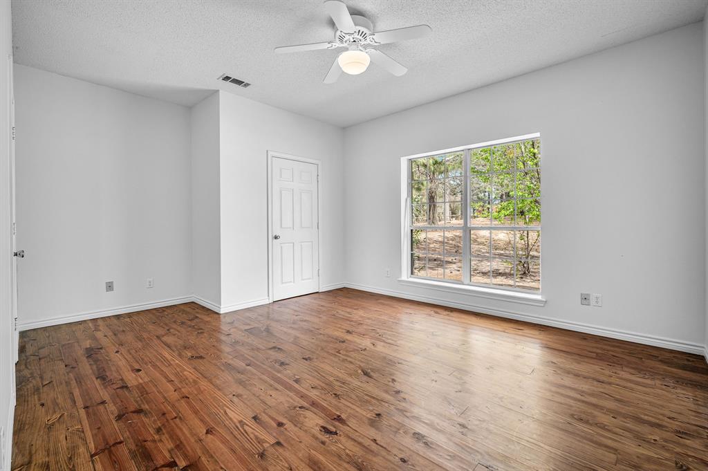 5327 Dusty Road Athens, TX 75752 - Photo 23 of 35 an empty room with wooden floor chandelier fan and windows