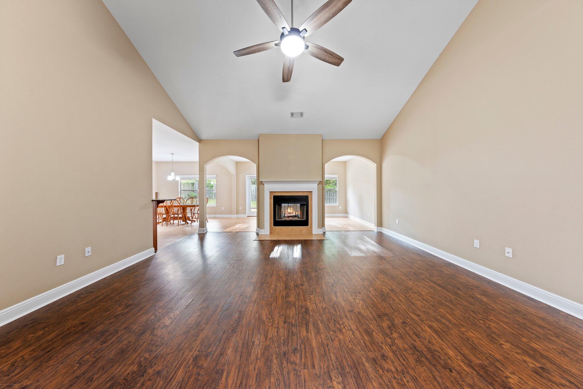 613 Red Fern Road Crestview, FL 32536 - Photo 20 of 39 a view of a livingroom with wooden floor a ceiling fan a fireplace and windows