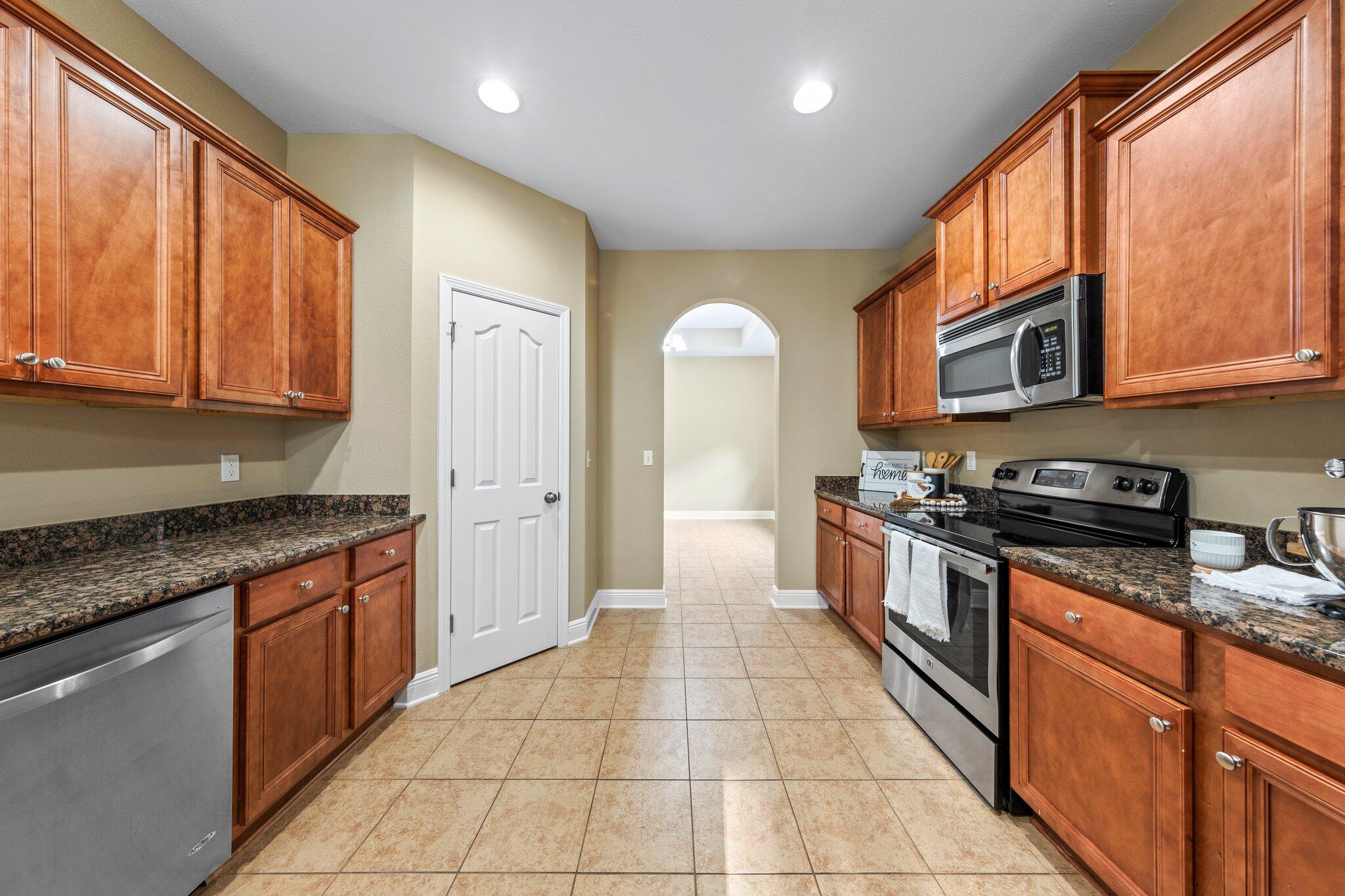 613 Red Fern Road Crestview, FL 32536 - Photo 27 of 39 a large kitchen with stainless steel appliances granite countertop a stove a sink and a microwave