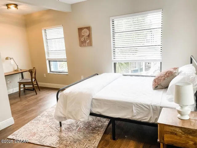a bedroom with a bed a lamp and wooden floor