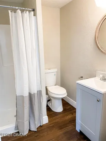 a bedroom with a bed a dresser and wooden floor