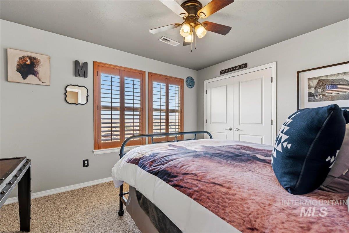 11660 Timber Butte Road Sweet, ID 83670 - Photo 21 of 49 Two windows with wood-finish plantation shutters, a ceiling fan with light fixture, and double paneled doors