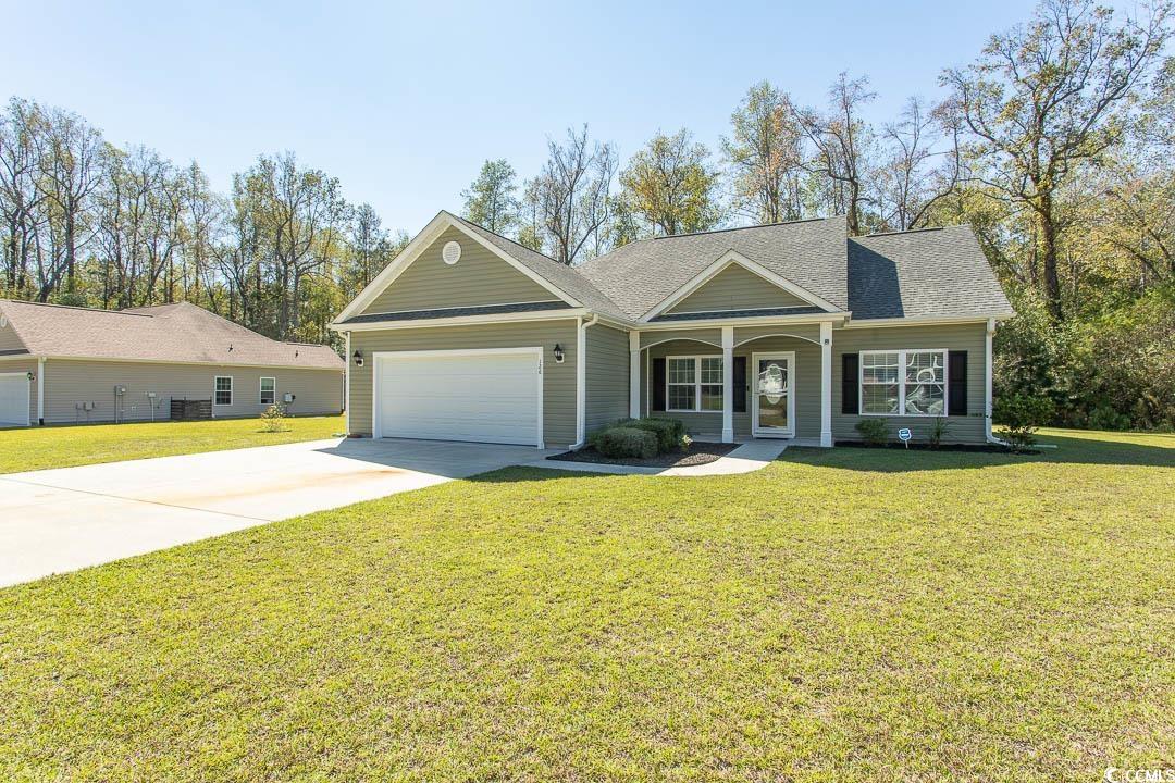 View of front facade featuring a front yard, driveway, a porch, a garage, and a shingled roof