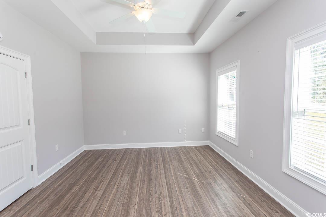 126 Allsbrook Road Loris, SC 29569 - Photo 24 of 30 Spare room with dark wood-style flooring, a tray ceiling, and a ceiling fan