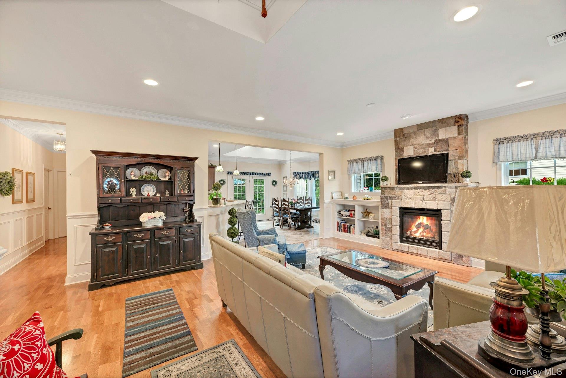 159 Stoneleigh Drive Riverhead, NY 11901 - Photo 12 of 24 Living room with light wood-style flooring, ornamental molding, a fireplace, recessed lighting, and wainscoting