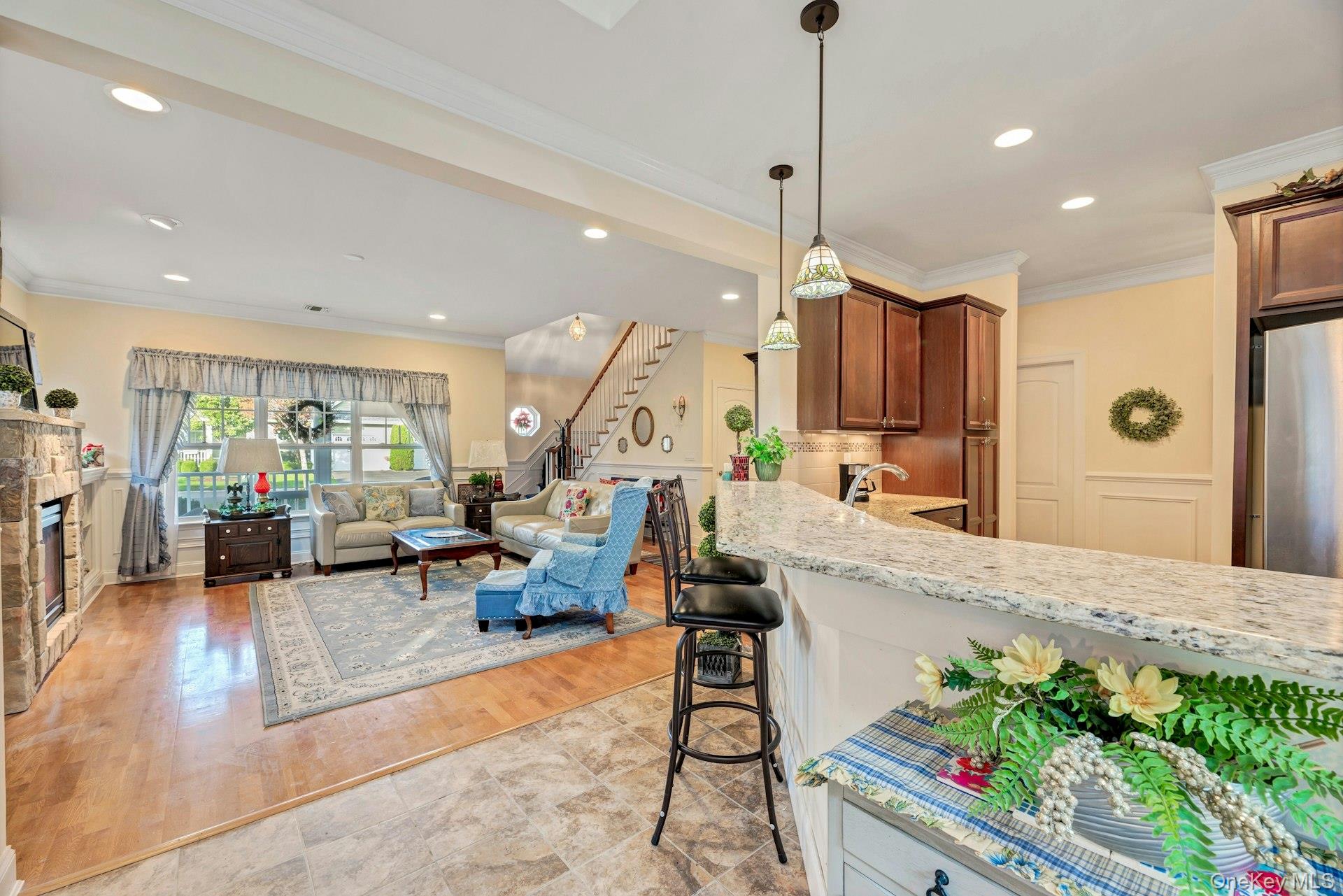 159 Stoneleigh Drive Riverhead, NY 11901 - Photo 24 of 24 Kitchen featuring ornamental molding, a kitchen breakfast bar, light stone countertops, open floor plan, and pendant lighting