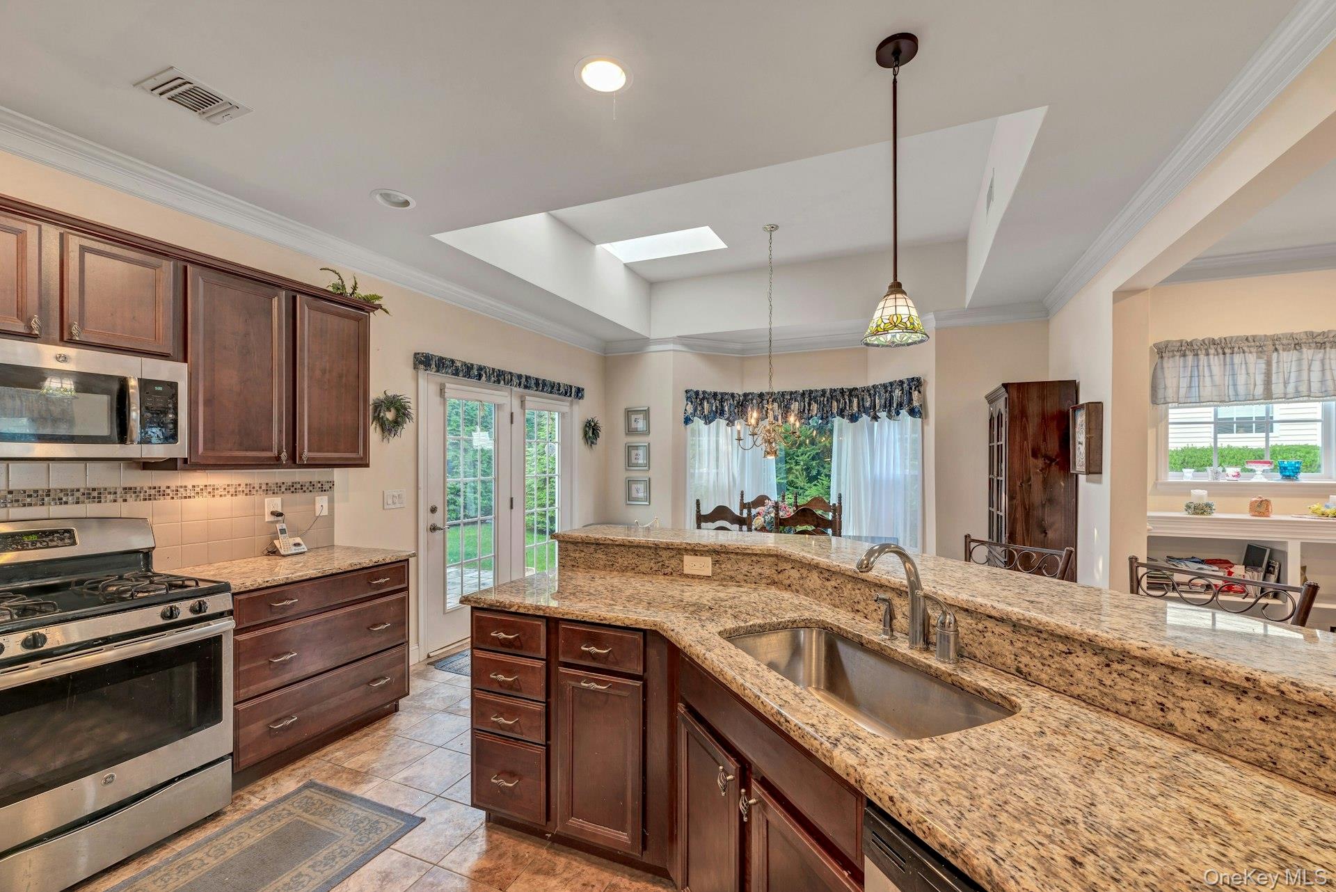 159 Stoneleigh Drive Riverhead, NY 11901 - Photo 18 of 24 Kitchen featuring a raised ceiling, stainless steel appliances, a skylight, light stone counters, and backsplash