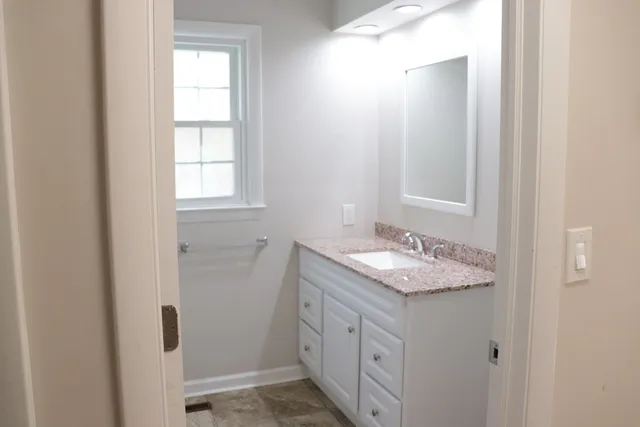 a bathroom with a granite countertop sink and a window