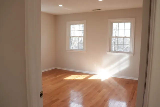 an empty room with wooden floor and windows