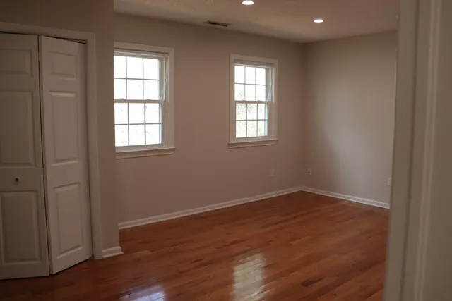 an empty room with wooden floor and windows