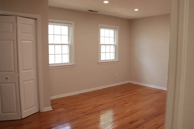 an empty room with wooden floor and windows