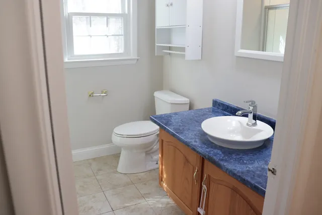 a bathroom with a granite countertop sink and a toilet