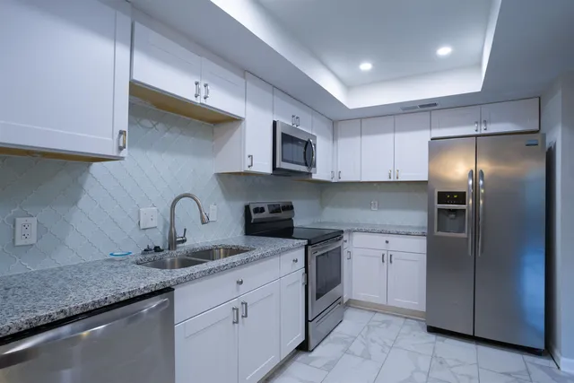 a kitchen with stainless steel appliances granite countertop a sink a stove and a refrigerator