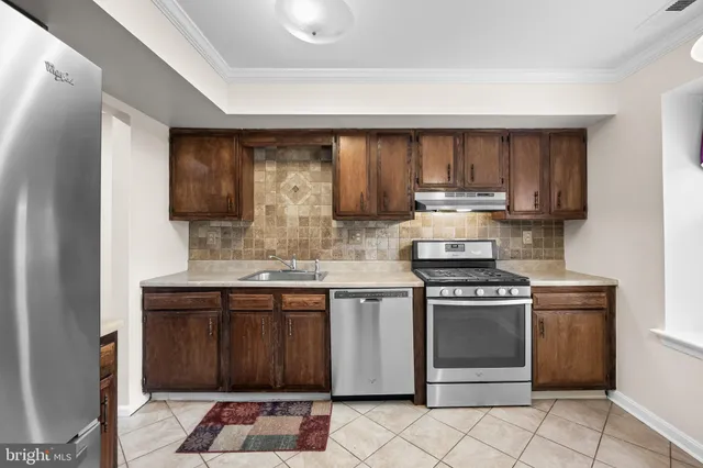a kitchen with stainless steel appliances granite countertop wooden cabinets stove top oven and sink