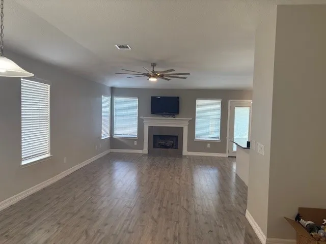 an empty room with fireplace wooden floor and windows