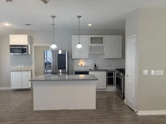 a large kitchen with stainless steel appliances kitchen island a large counter top and a wooden floors