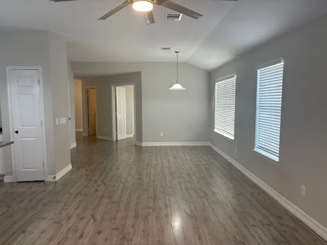an empty room with wooden floor and windows
