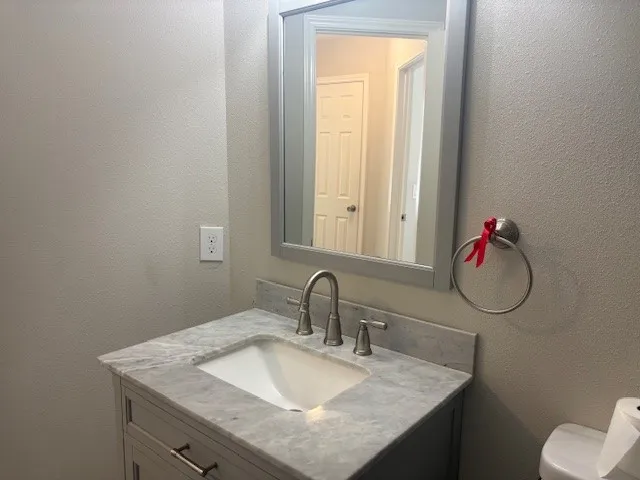 a bathroom with a granite countertop sink and a mirror
