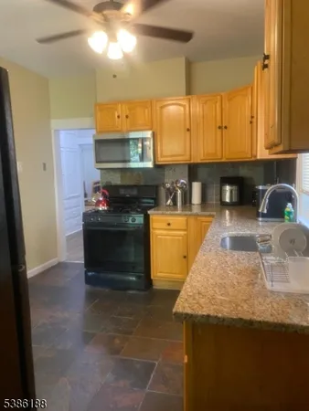 a kitchen with granite countertop a sink a stove and a wooden cabinets