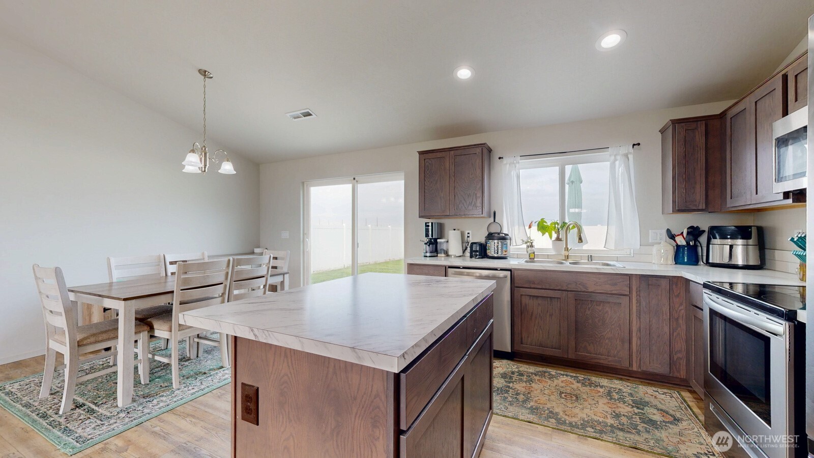 907 East Cascade Street Othello, WA 99344 - Photo 6 of 27 a kitchen with granite countertop a table chairs stove microwave and cabinets
