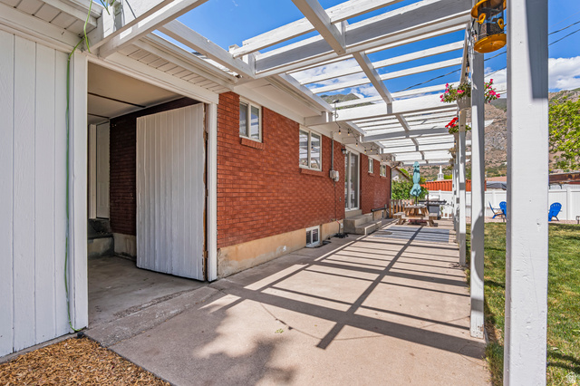 480 North 150 E Street Springville, UT 84663 - Photo 35 of 36 Covered patio area with a slatted pergola, red brick exterior, concrete patio surface, and a white privacy fence