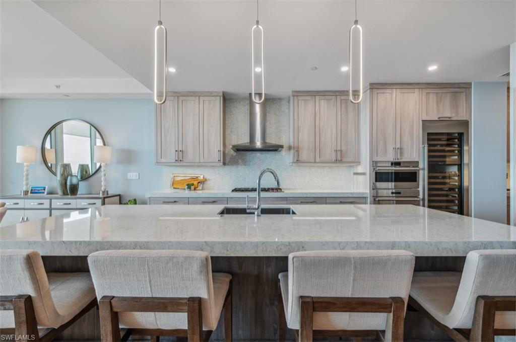 13925 Old Coast Road, Unit PH02 Naples, FL 34110 - Photo 16 of 33 a kitchen with a dining table chairs and cabinets