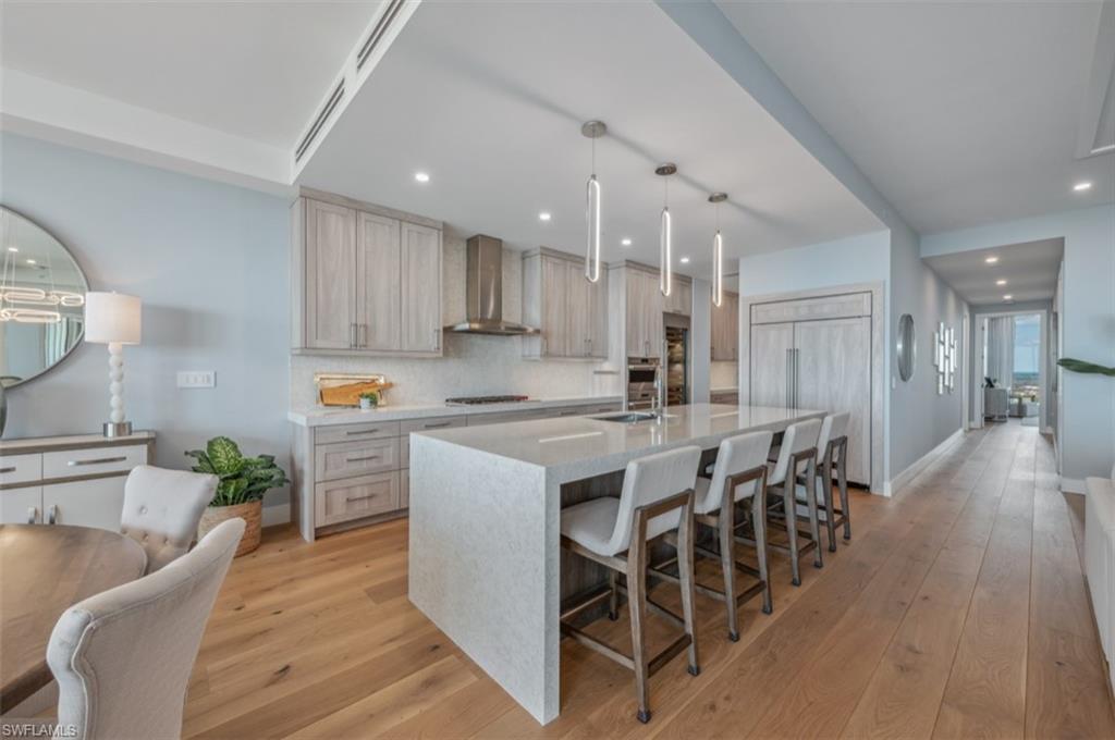 13925 Old Coast Road, Unit PH02 Naples, FL 34110 - Photo 20 of 33 a kitchen with stainless steel appliances kitchen island granite countertop a table chairs sink and cabinets