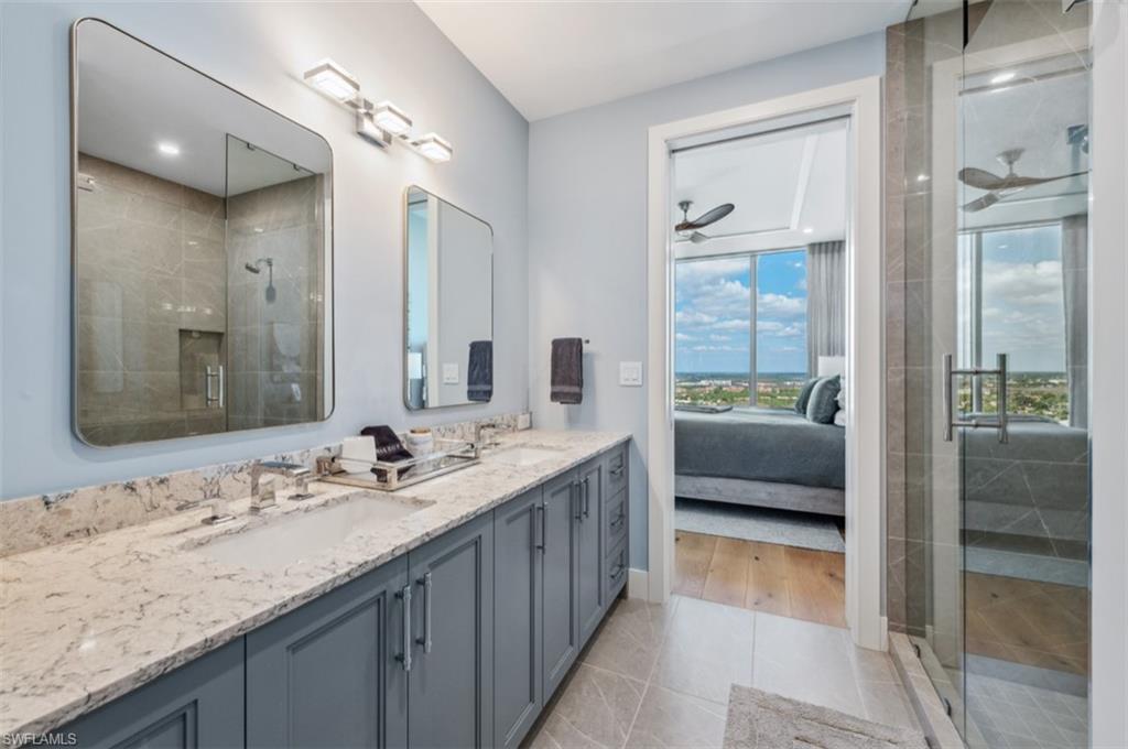 13925 Old Coast Road, Unit PH02 Naples, FL 34110 - Photo 28 of 33 a en suite bathroom with a granite countertop double vanity sink and a large mirror